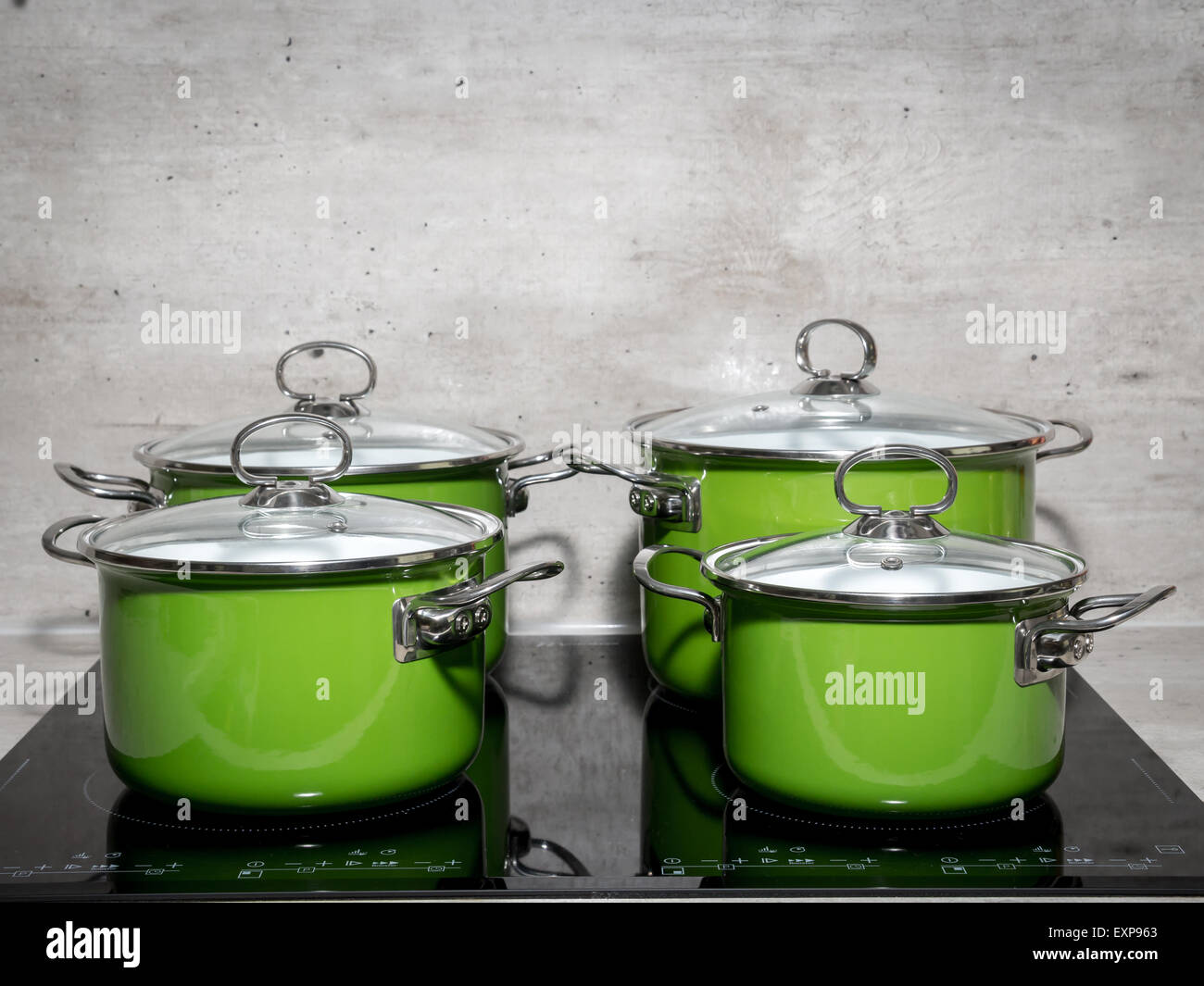 Quattro di smalto verde stewpots su nero fornello ad induzione Foto Stock