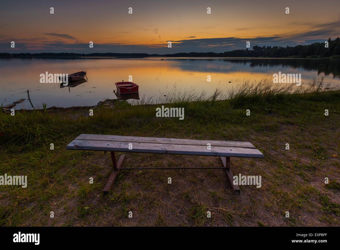 Il bel lago tramonto con barche di pescatori e panca sulla riva. Lago polacco in Mazury Lake District. Polacco paesaggio del lago Foto Stock