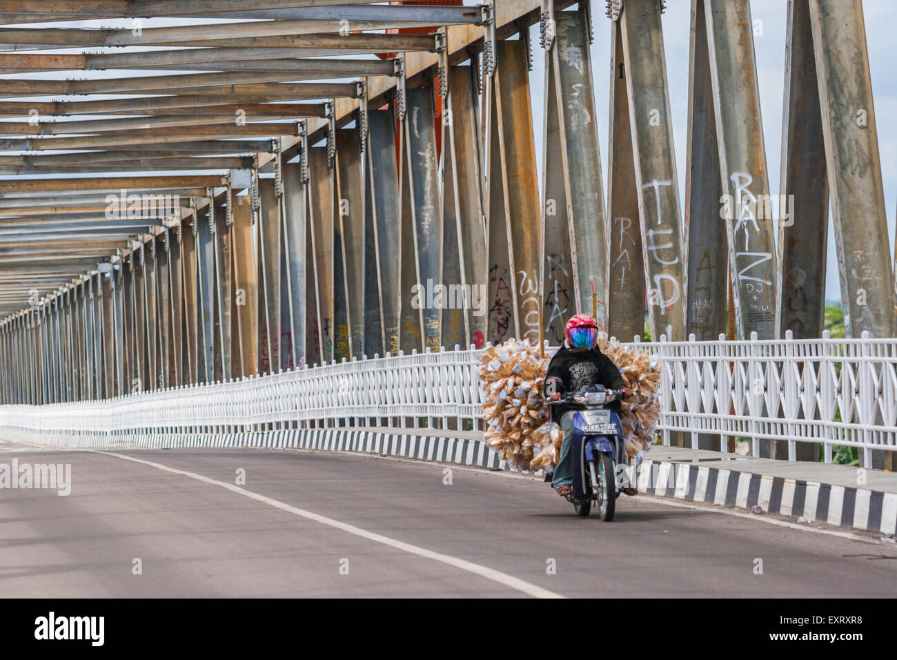 Motorbiker passando attraverso il ponte Kahayan che trasporta carichi a Palangkaraya, Kalimantan centrale, Indonesia. Foto Stock