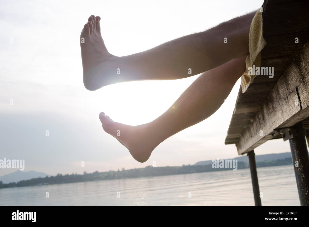 Uomo su una dock tenendo i piedi in aria nella sera sun Foto Stock