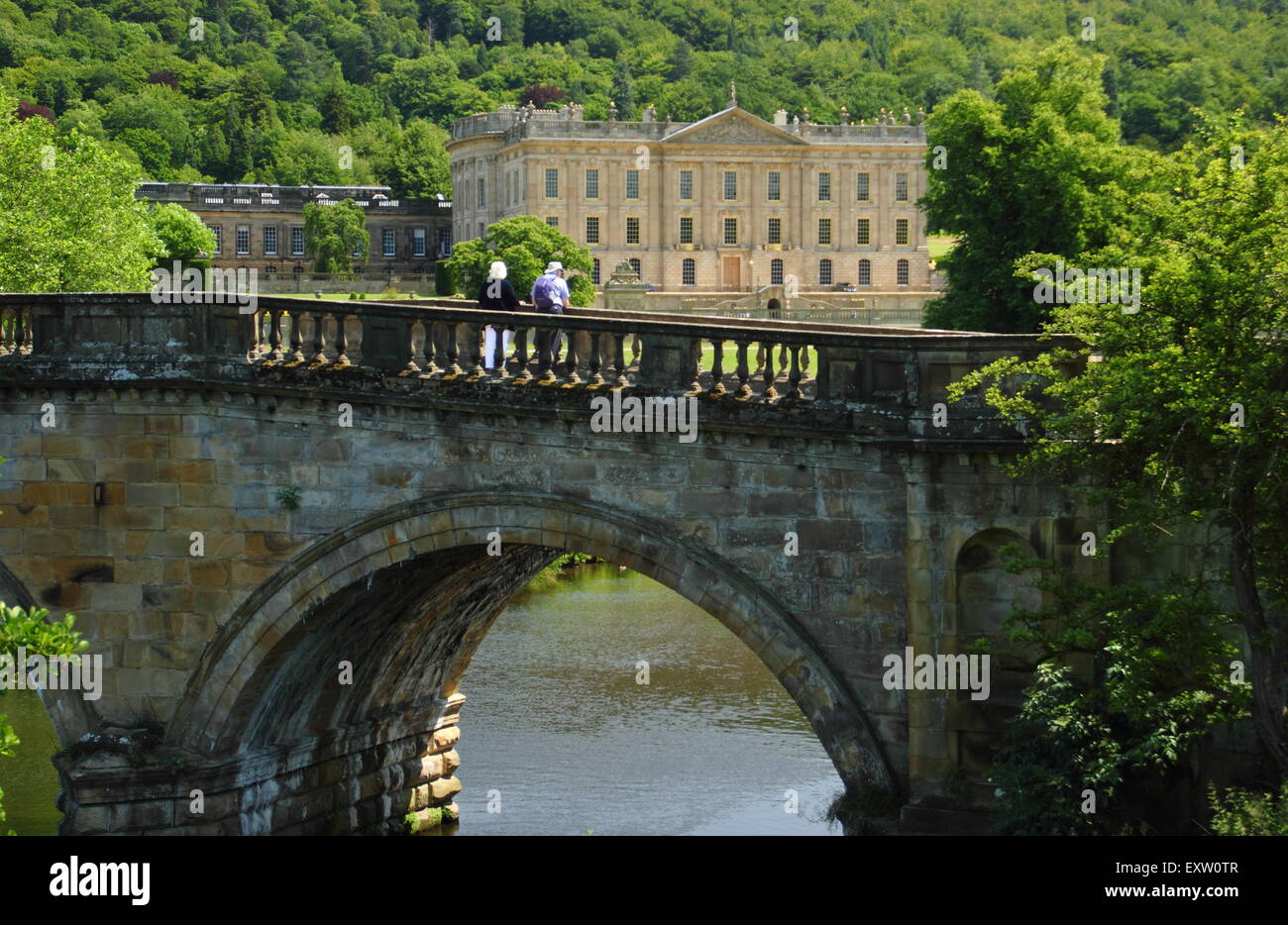 I visitatori a Chatsworth House su un ponte arcuato sulla strategia principale per il Derbyshire maestosa casa Derbyshire England Regno Unito Foto Stock