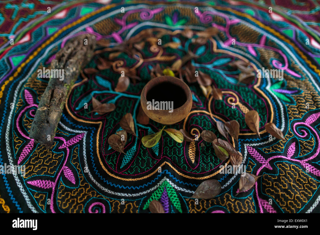 Una tazza utilizzata per servire ayahuasca siede su un tella ricamato in locali tradizionali disegni shipibo all'interno di un cerimoniale di maloca. Foto Stock