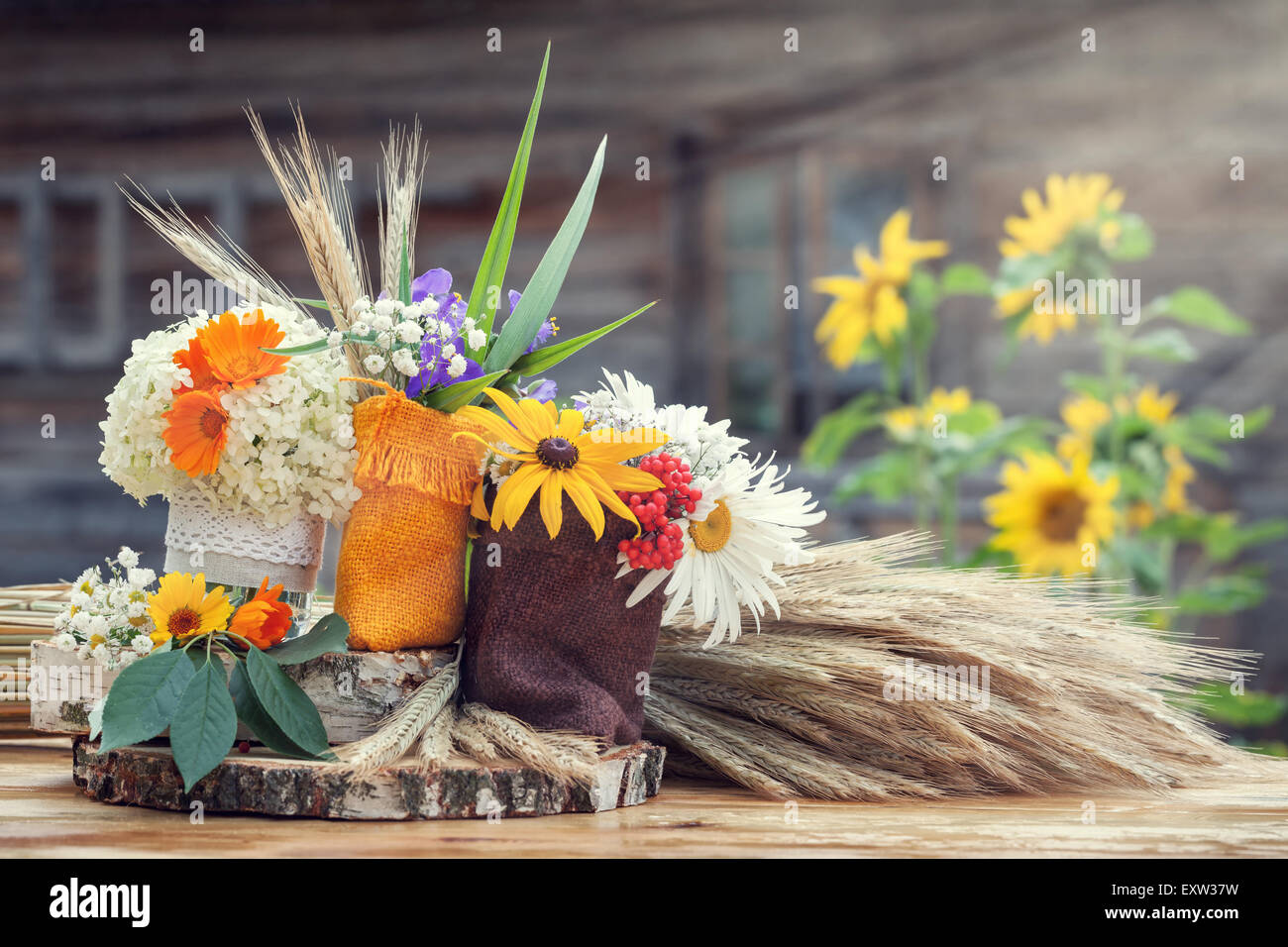 Decorazioni per matrimoni in stile rustico. Natura morta con fiori estivi in sacchetti e spighe di grano. Foto Stock