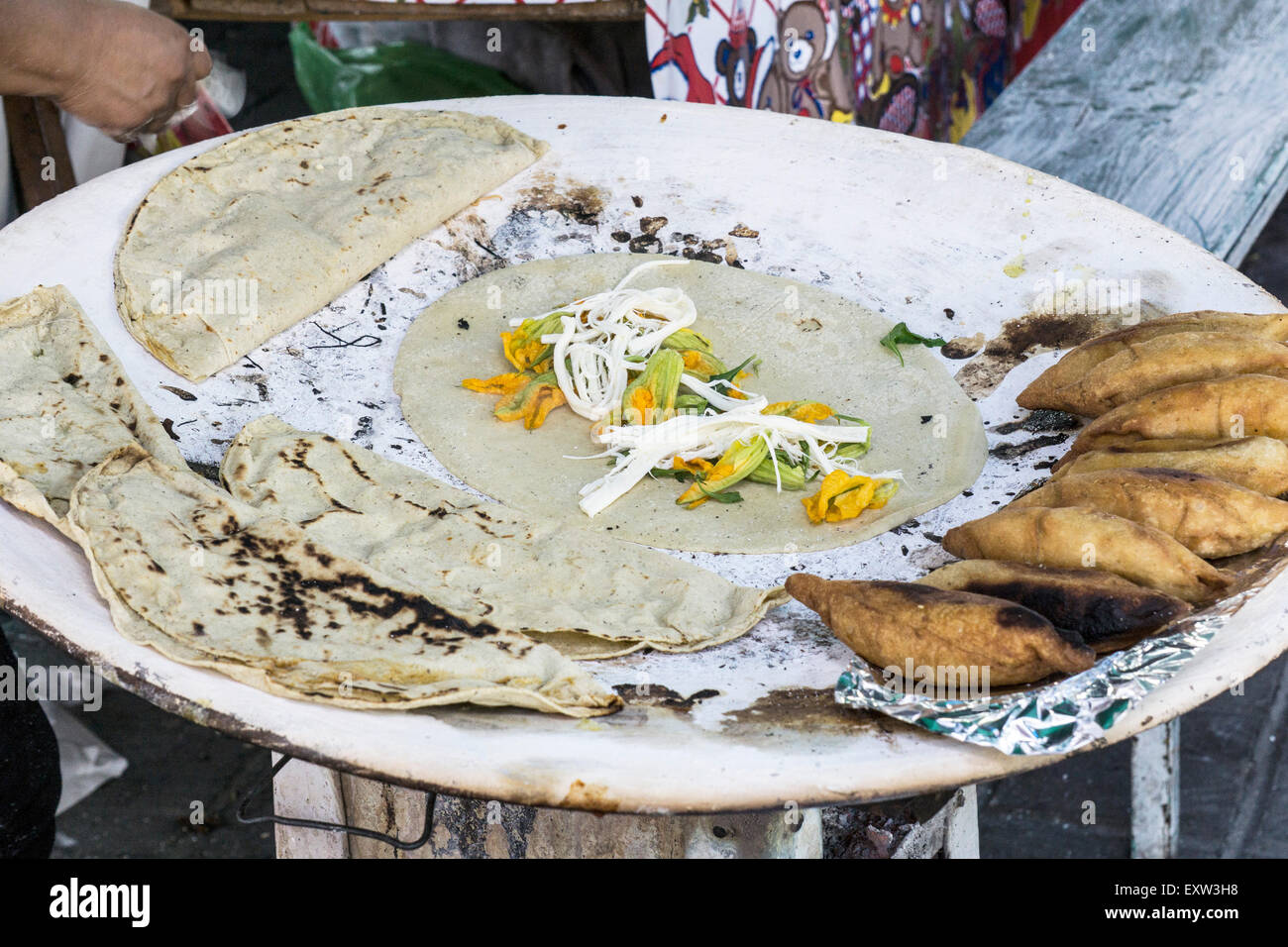 Taco con yummy fiori di zucca & string ripieno di formaggio street la cottura del cibo su una rudimentale stufa a carbone con le empanadas Oaxaca Foto Stock
