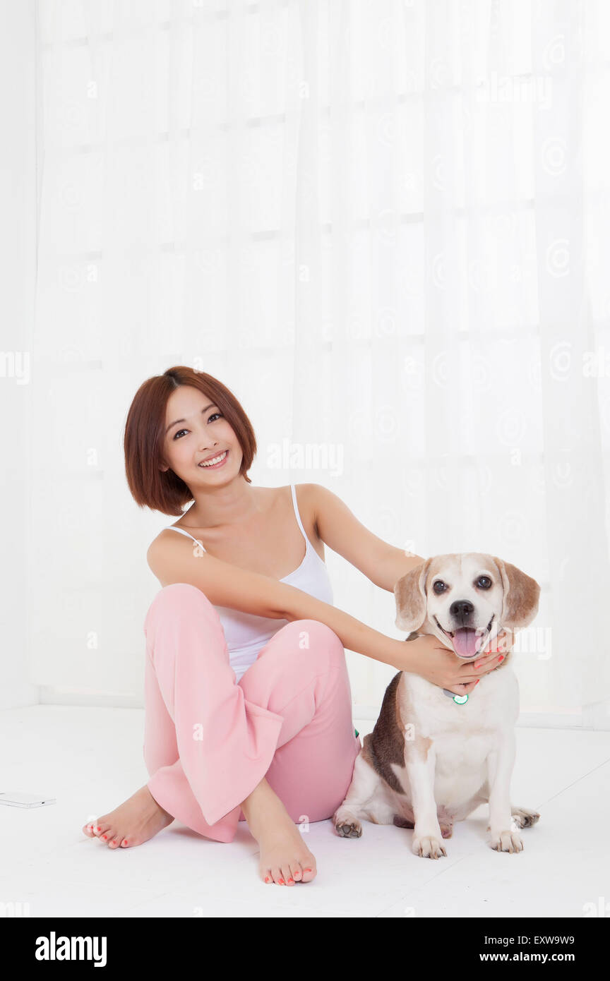 Giovane donna seduta con il cane e sorridente alla telecamera, Foto Stock