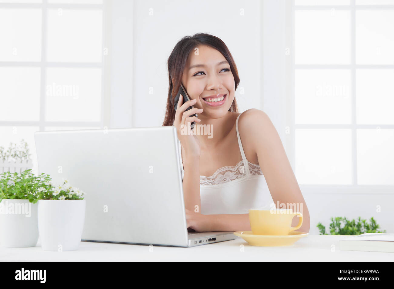 Giovane donna che guarda lontano con il sorriso e sul telefono, Foto Stock