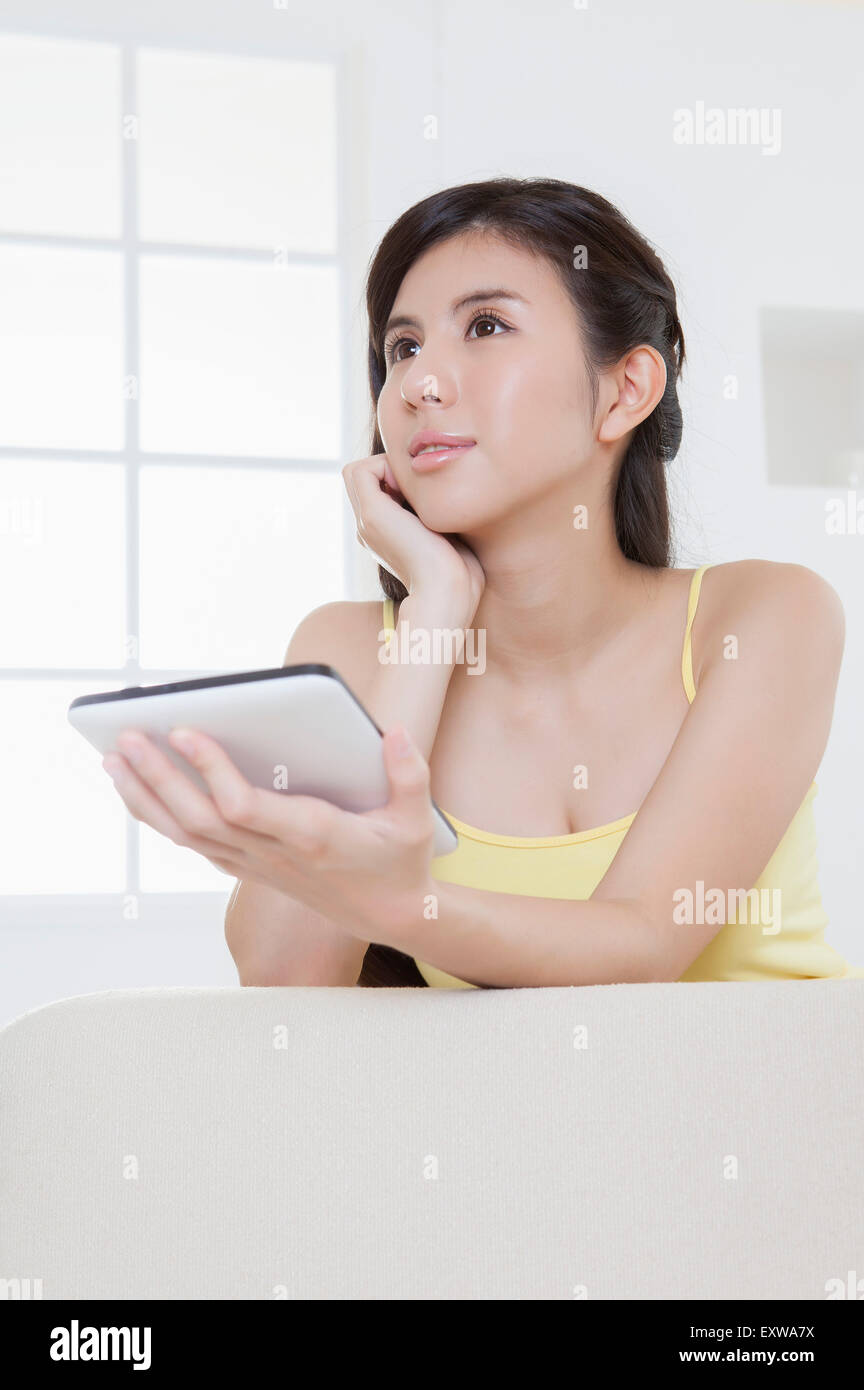Giovane donna tenendo premuto il touch pad e guardando lontano, Foto Stock