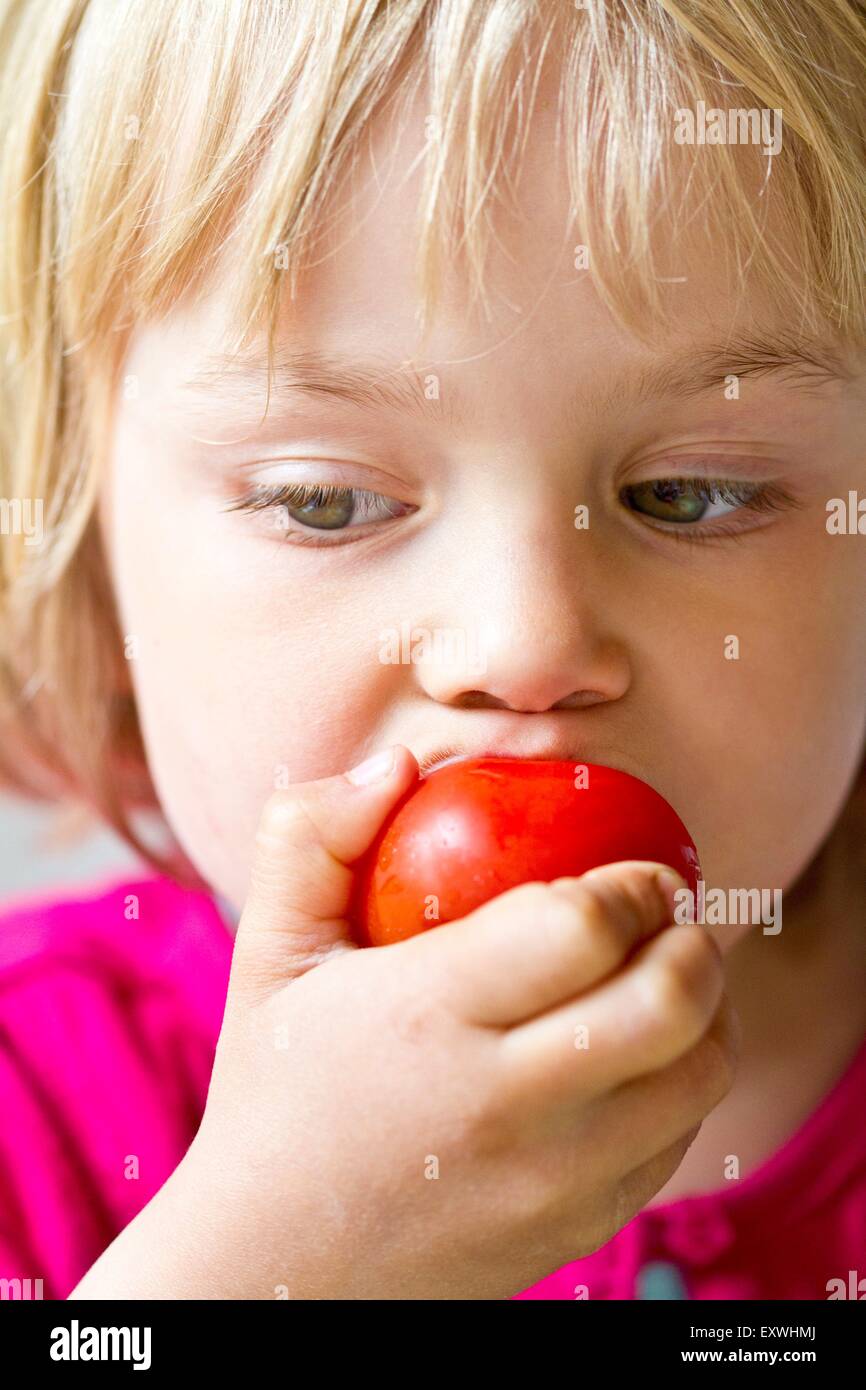 Ragazza di mangiare un pomodoro Foto Stock