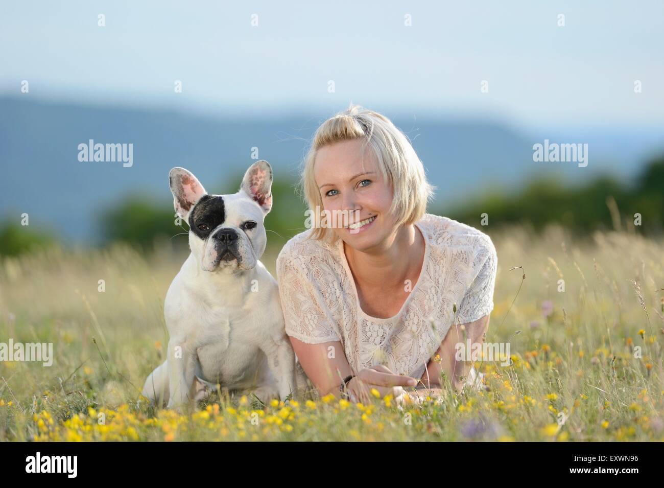 Donna sdraiata sul prato con un sette mesi bulldog francese Foto Stock