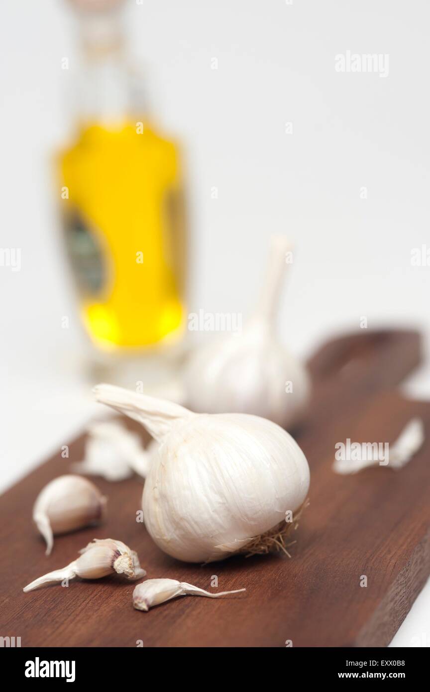 Bottiglia di olio e aglio guanti su una stecca Foto Stock