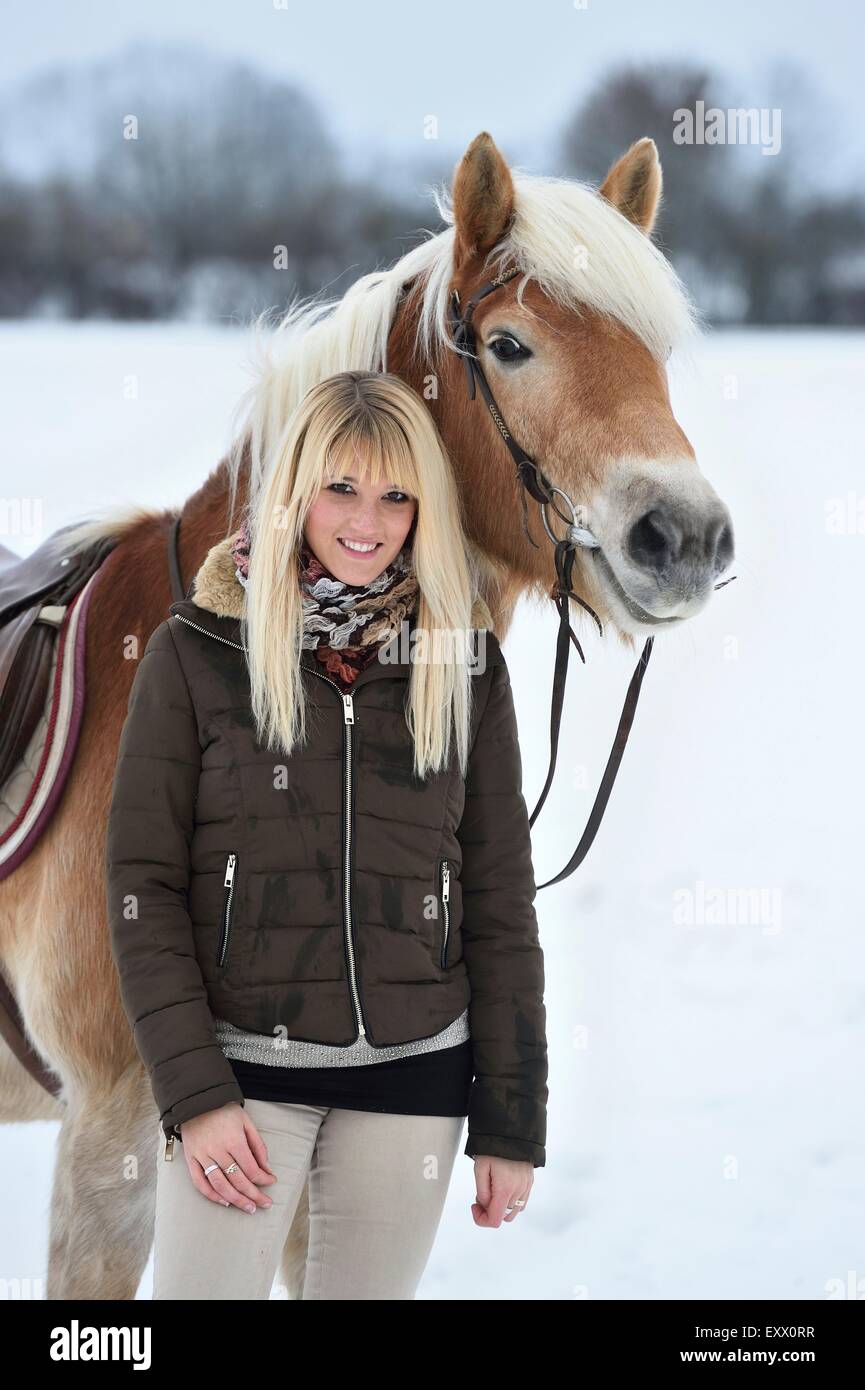 Giovane donna con cavalli di razza Haflinger nella neve Foto Stock
