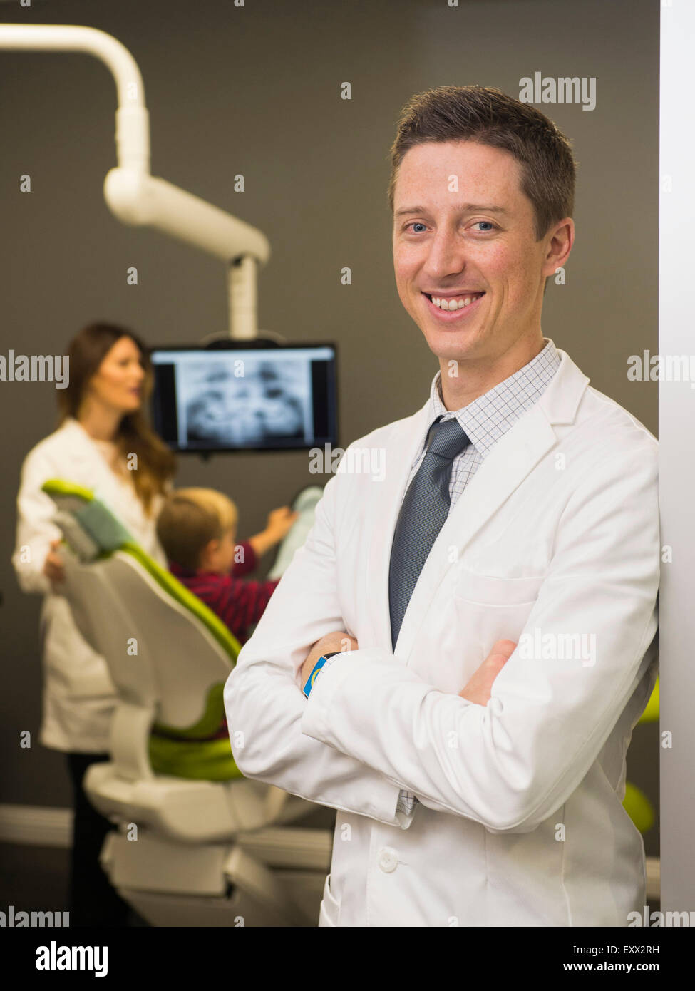 Ritratto di dentista con il collega e paziente (8-9) in background Foto Stock