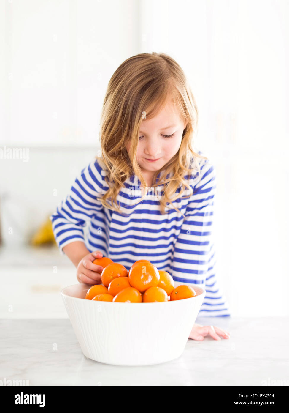 La ragazza (4-5) guardando le arance, sorridente Foto Stock