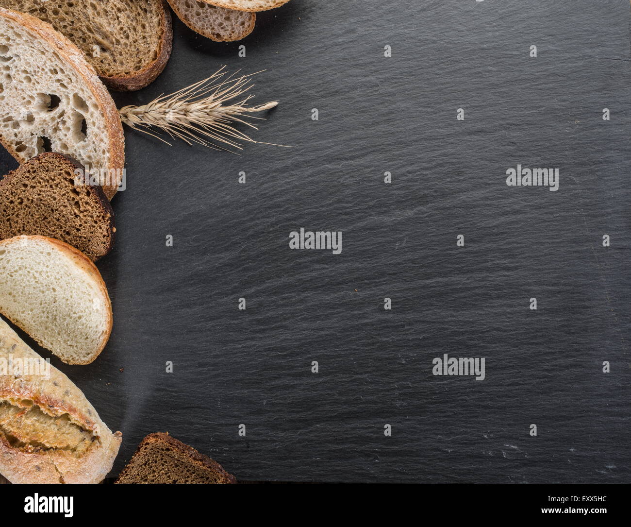 Le fette di pane, un grano e un coltello sulla pietra nera desk. Foto Stock
