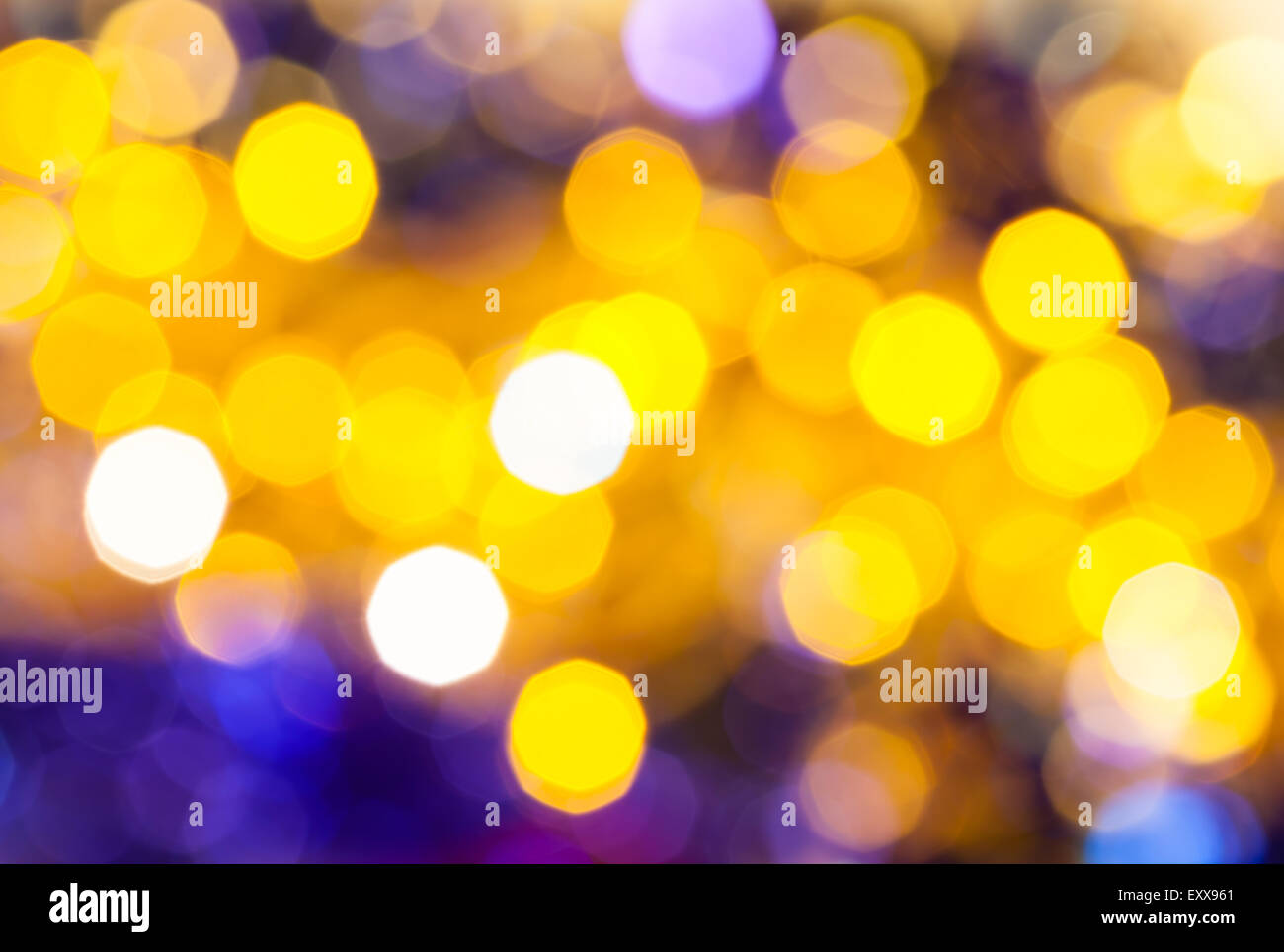 Abstract sfocare lo sfondo scuro - giallo e viola lo sfarfallio delle luci di Natale di le ghirlande elettriche su albero di Natale Foto Stock
