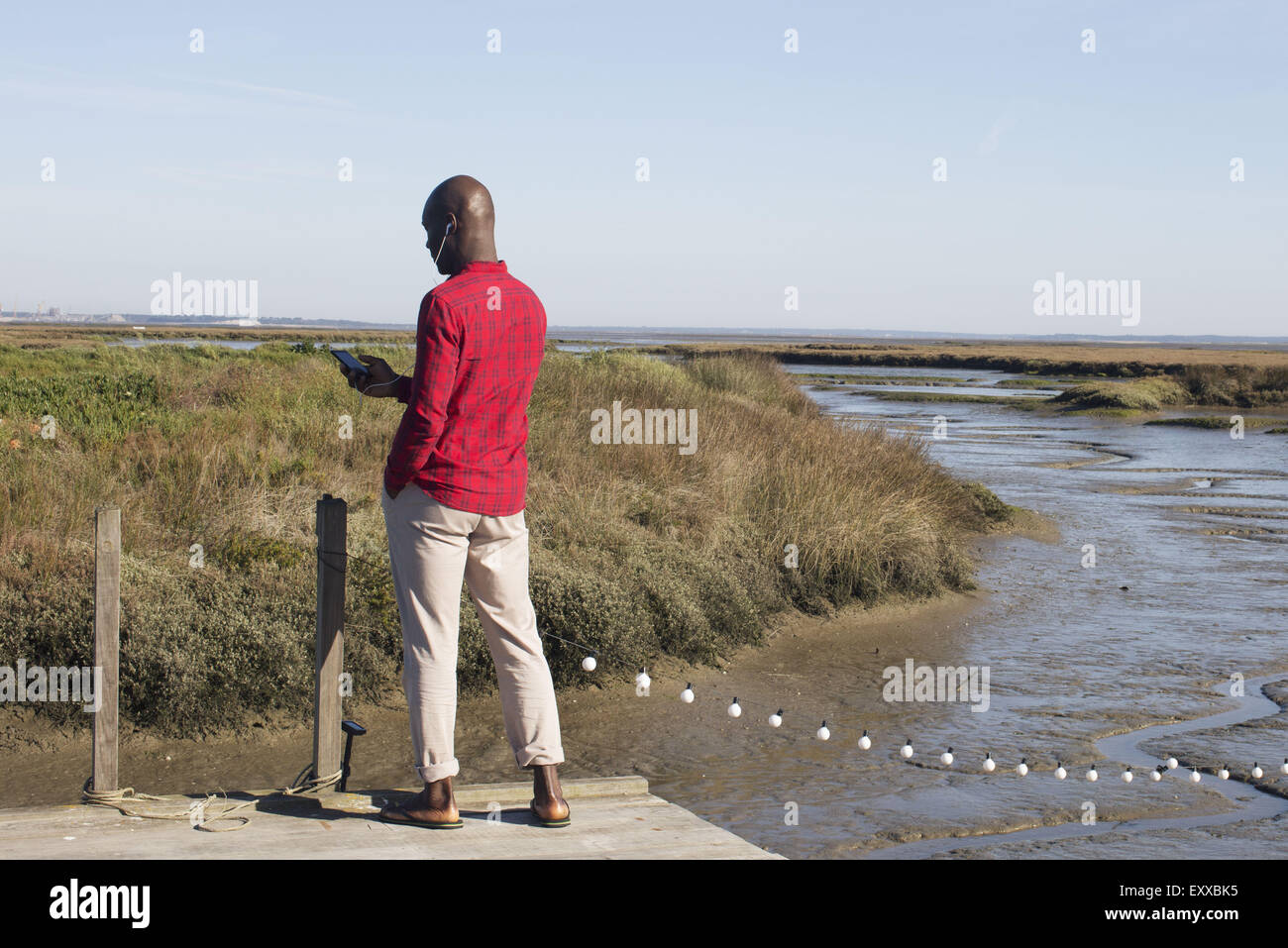 Uomo in piedi sul dock, ascoltando la musica con gli auricolari Foto Stock