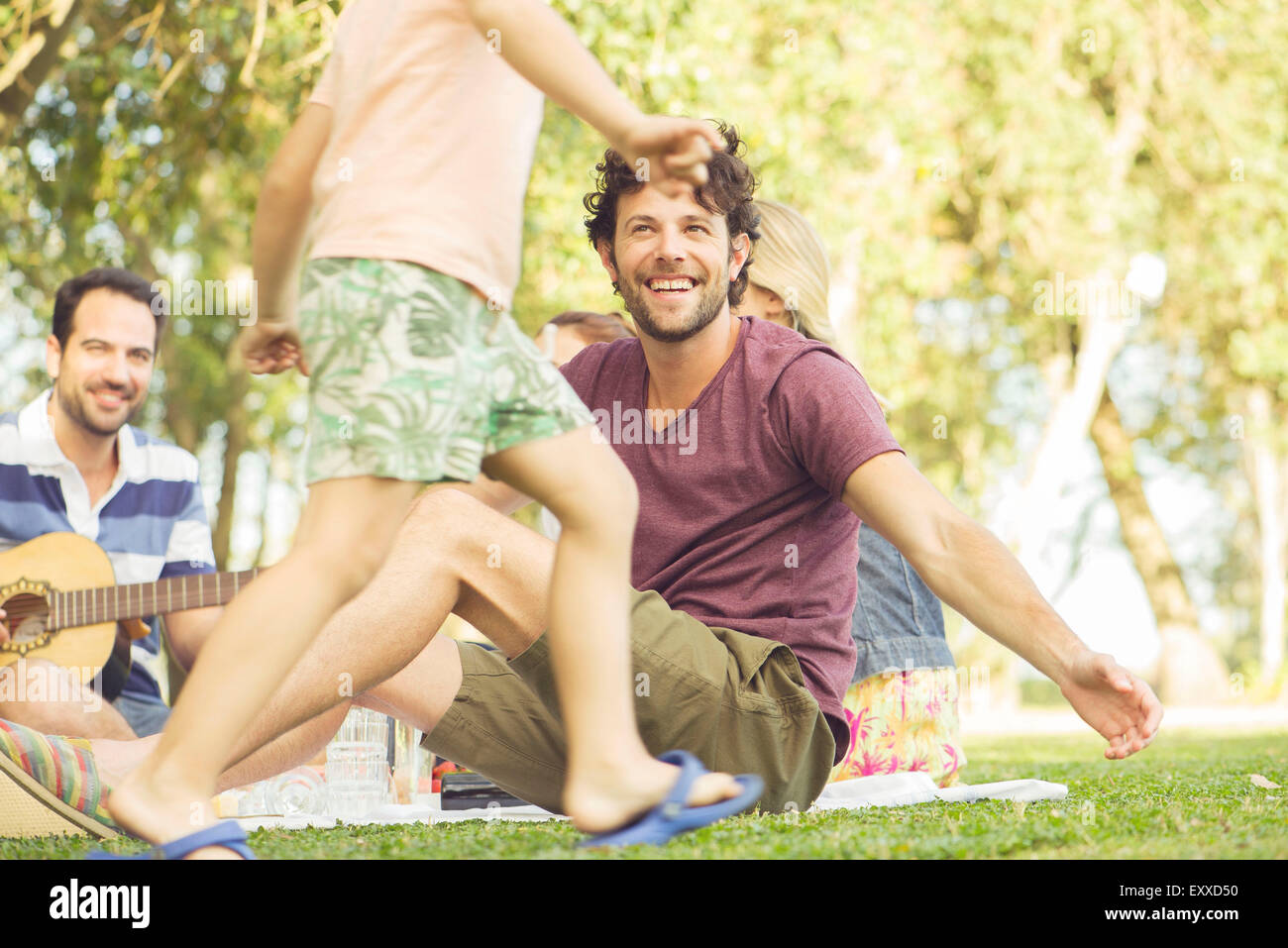 Uomo al picnic a guardare i bambini giocare Foto Stock
