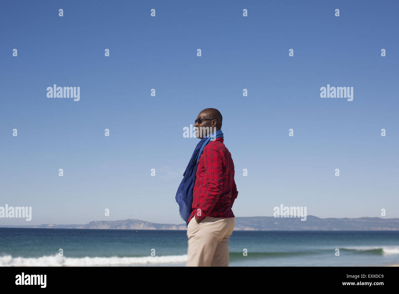 Uomo in piedi da sola sulla spiaggia, guardando a vista Foto Stock