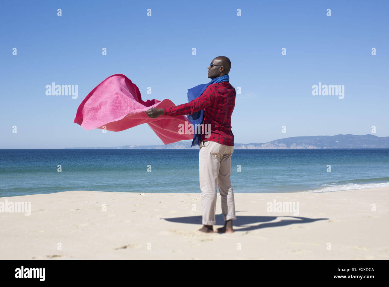 Uomo in spiaggia, tenendo coperta dalla brezza Foto Stock