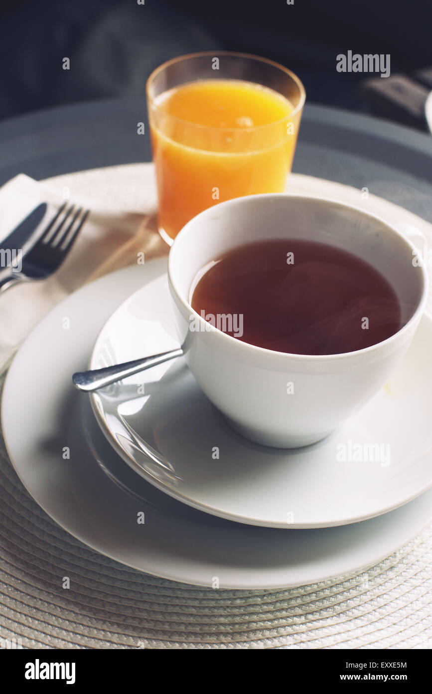 Tazza di tè caldo e un bicchiere di succo di arancia Foto Stock