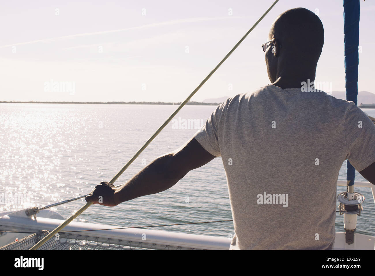 Uomo sulla barca vela, guardando a vista Foto Stock