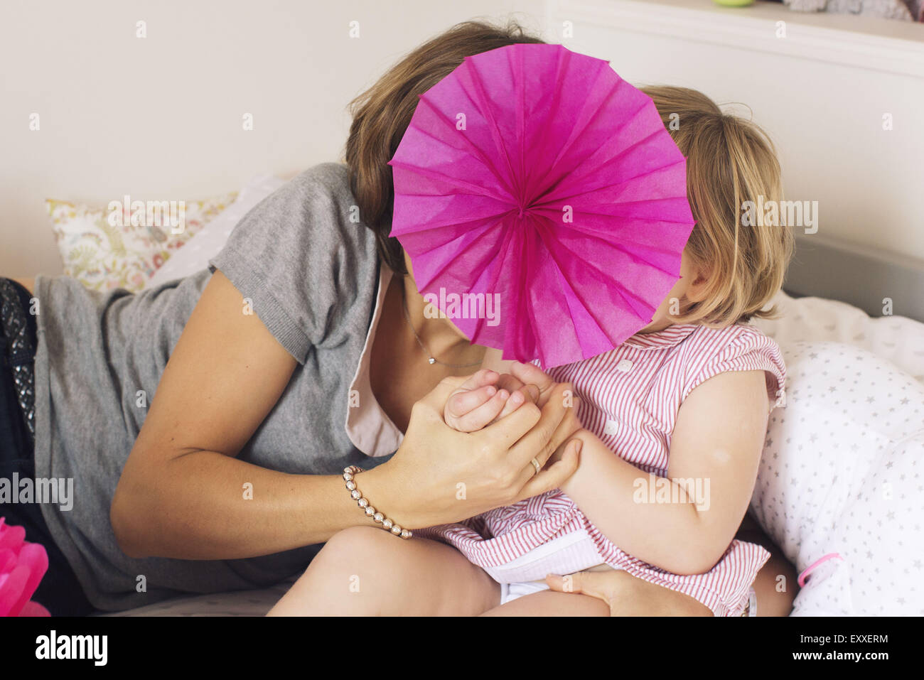 Madre e figlia di nascondersi dietro il tessuto di fiori di carta Foto Stock