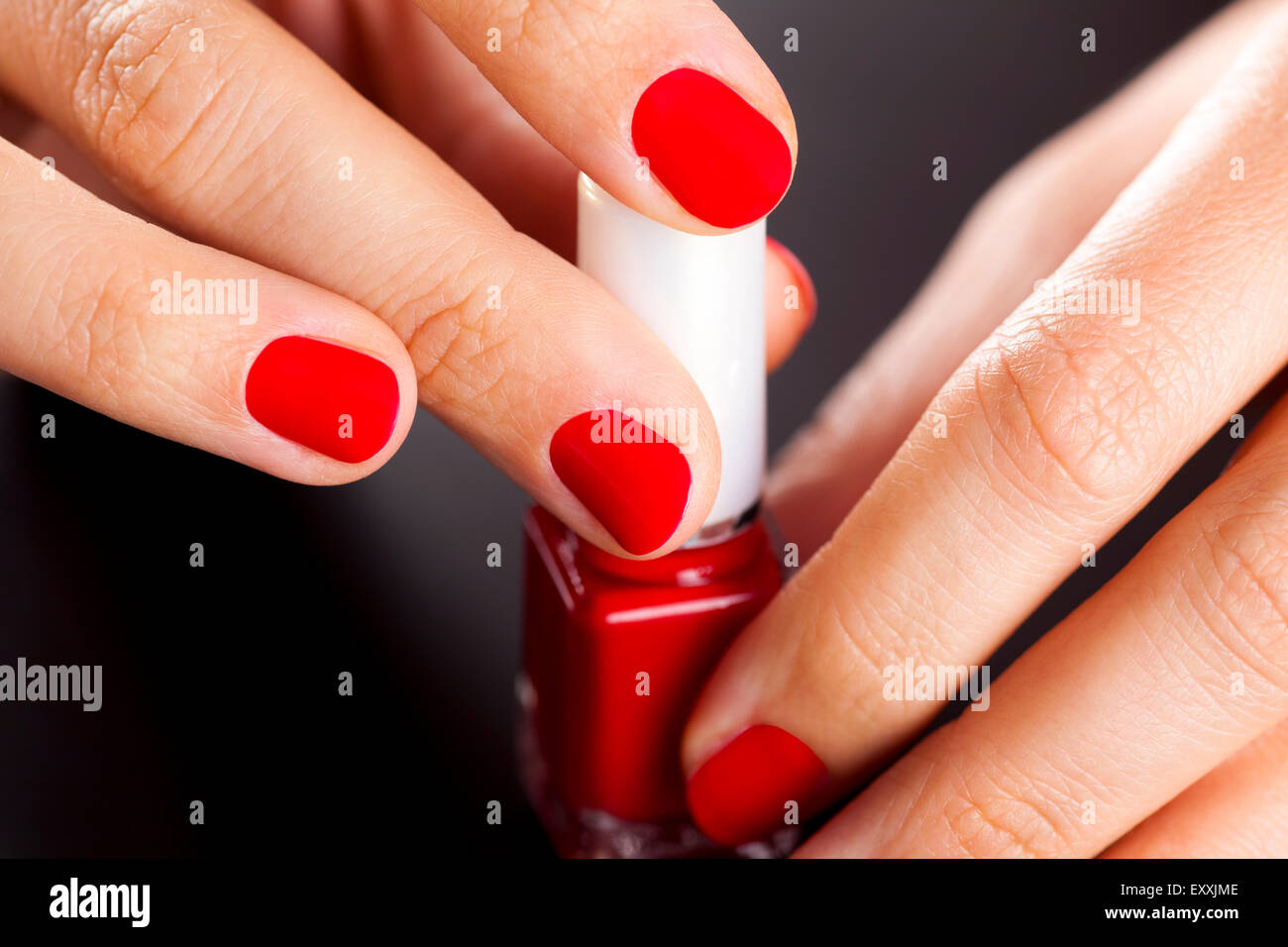 Bottiglia di Rosso di smalto per unghie in donna curati palms su sfondo nero. Foto Stock