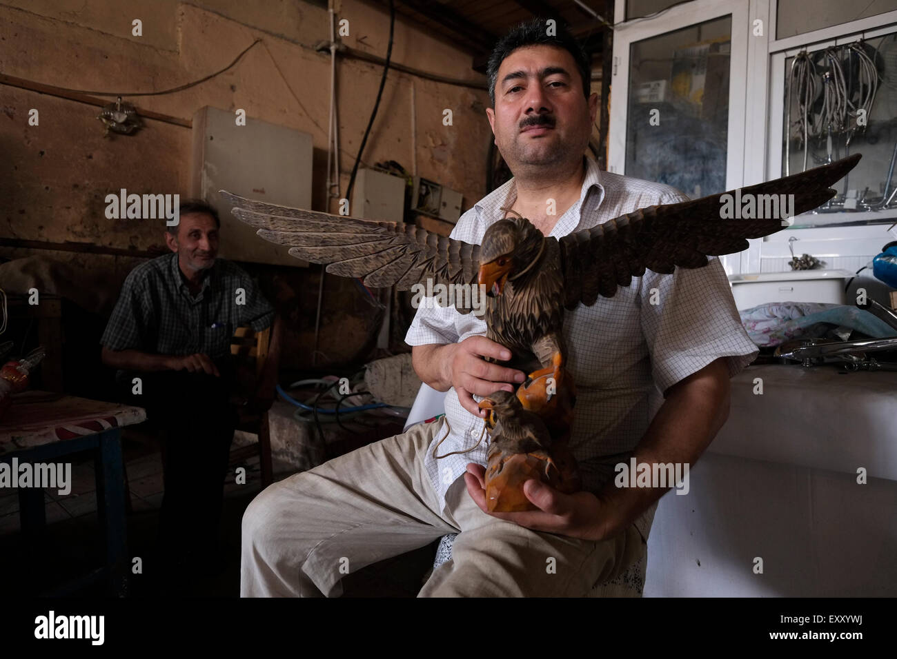 Un venditore detiene una figura scolpita di un'aquila Mercato di Taza Bazaar nella città di Baku in Azerbaigian Foto Stock