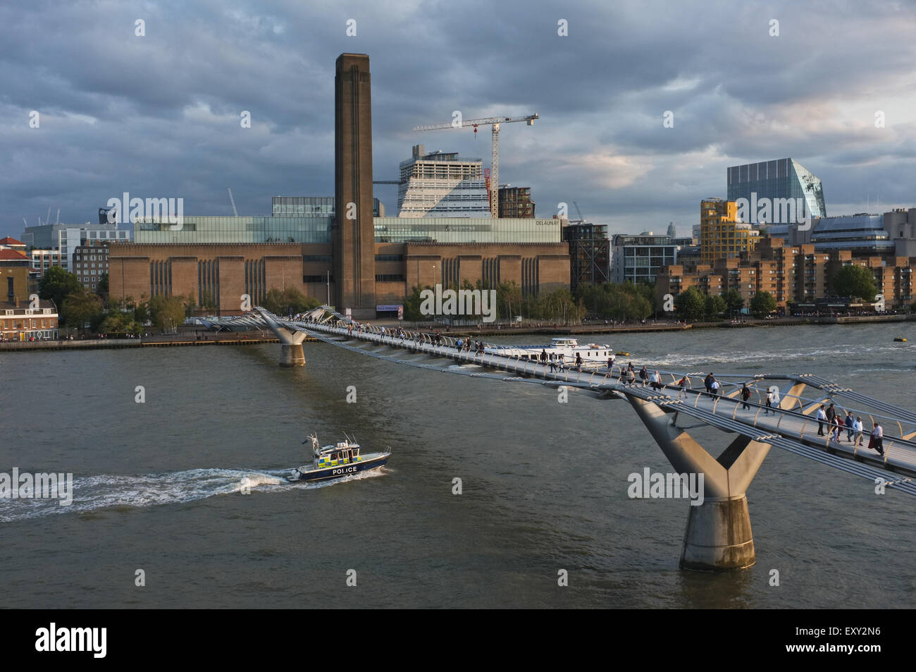 Il Millennium Bridge sul Tamigi che conduce alla Tate Modern di Londra. Un lancio di polizia sta per navigare sotto il ponte. Foto Stock