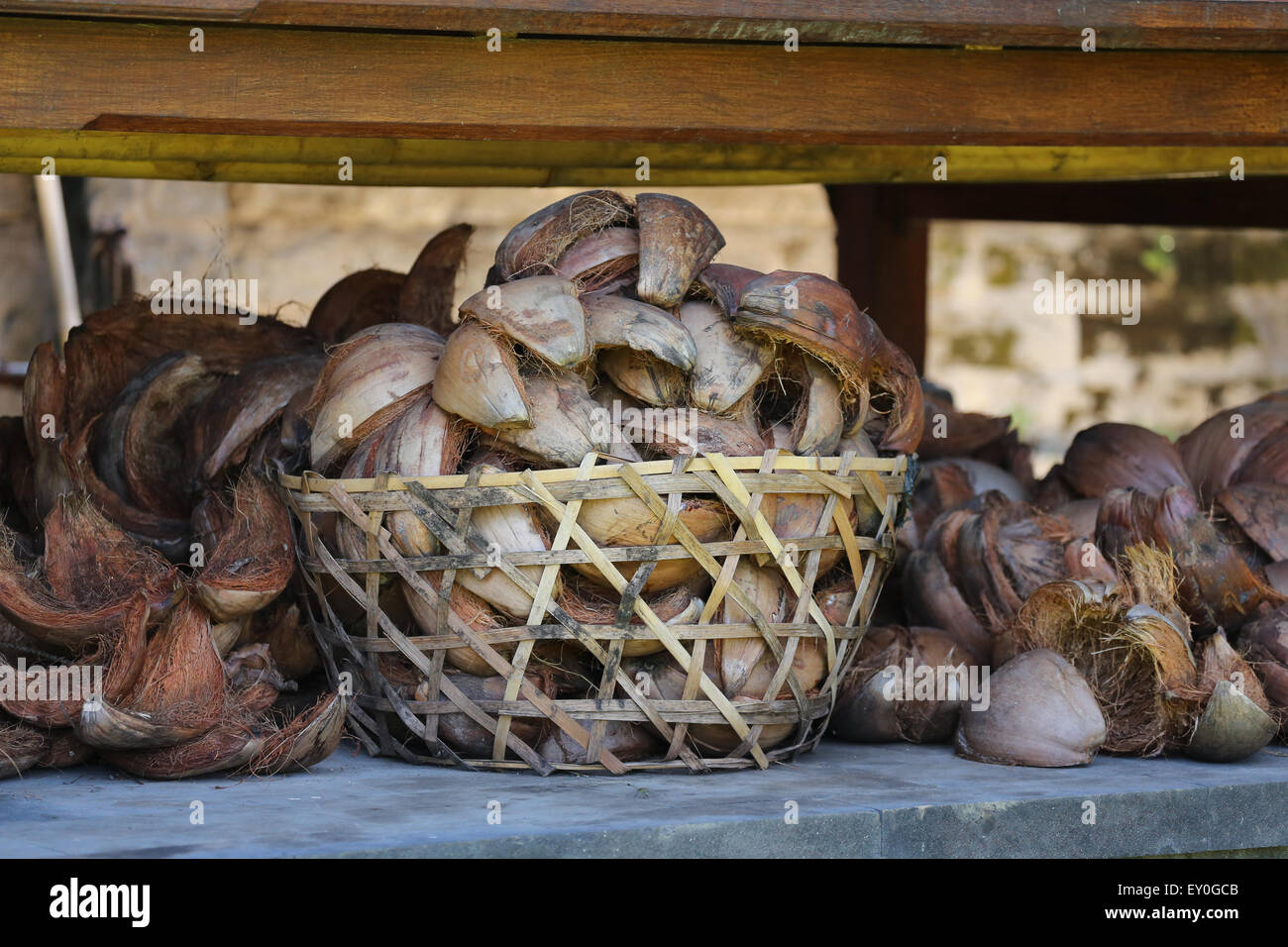 Treccia in legno cesto pieno di vuoto di gusci di noce di cocco. più gusci accanto al cestino, Foto Stock