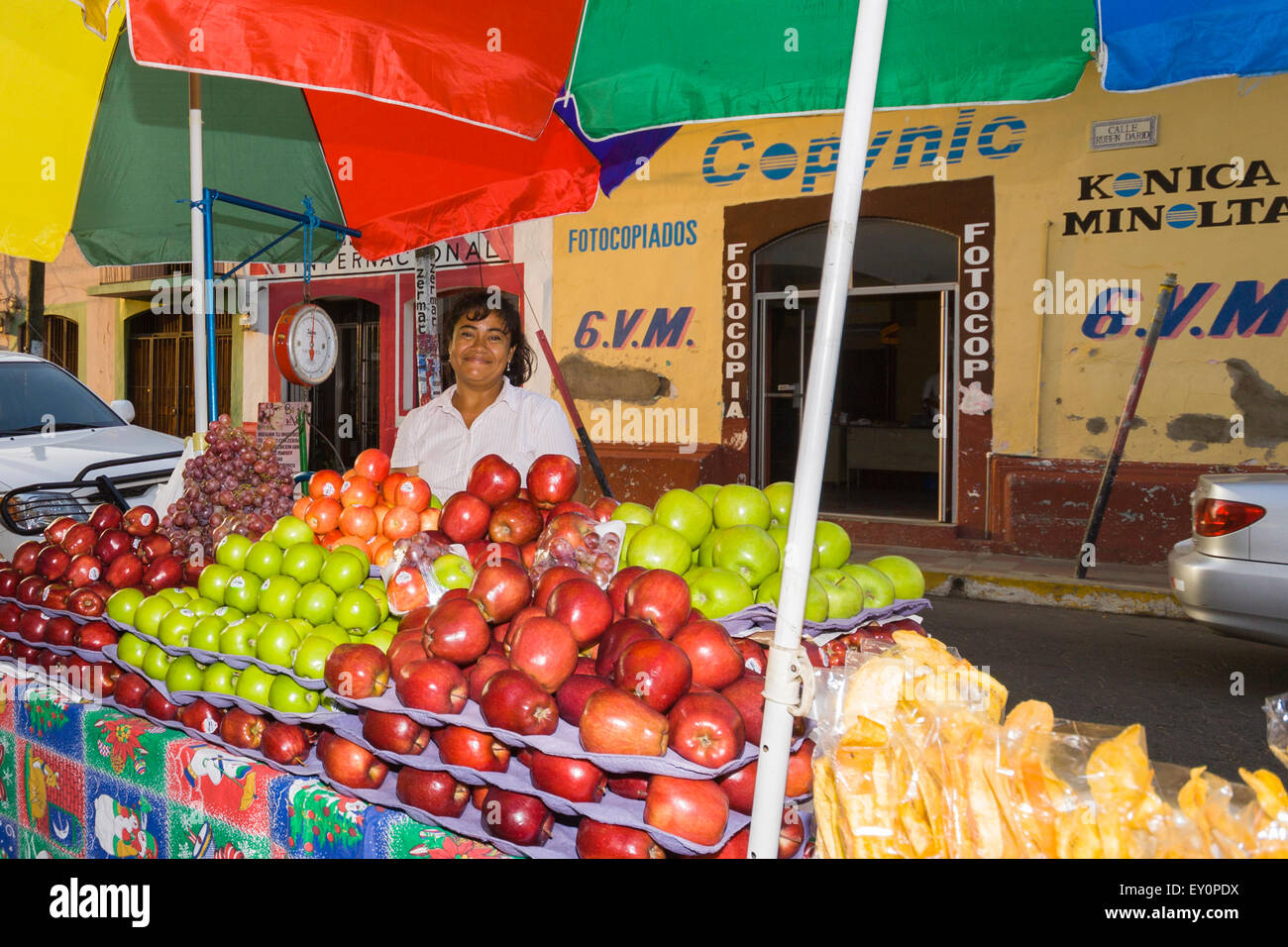Donna sorridente per la vendita di frutta in stallo colorati per le strade di León, Nicaragua Foto Stock