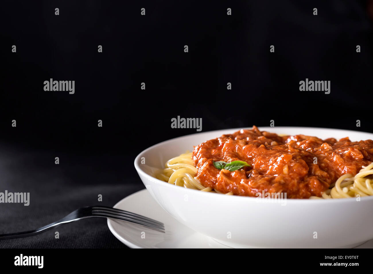 Spaghetti con sugo di tonno su sfondo nero con spazio di copia Foto Stock