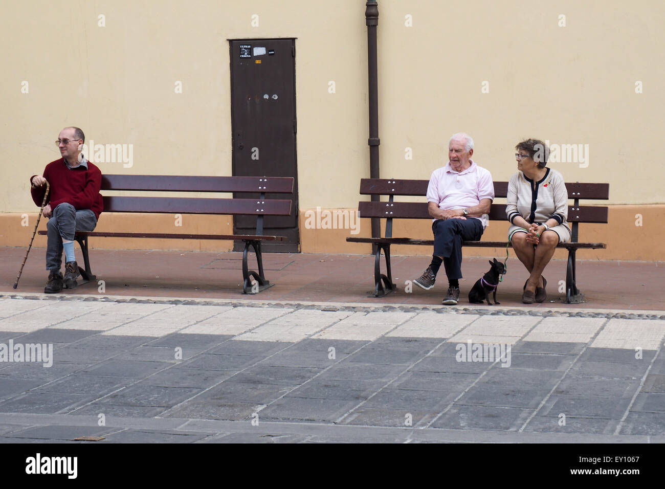 Tre persone sedute sui banchi di strada. Foto Stock