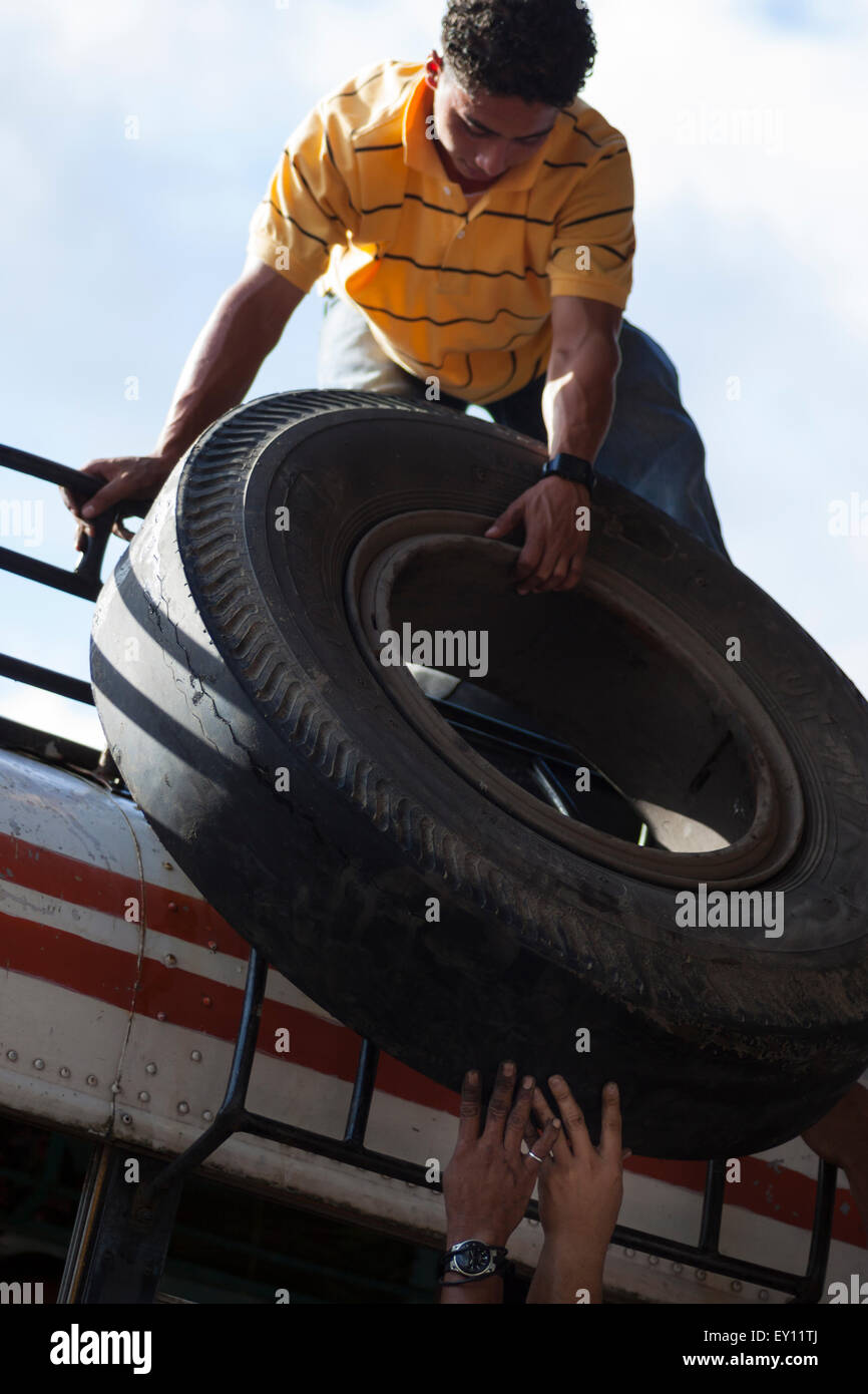 Gli uomini durante il download di una ruota di scorta da un autobus dalla stazione degli autobus di Rivas, Nicaragua Foto Stock