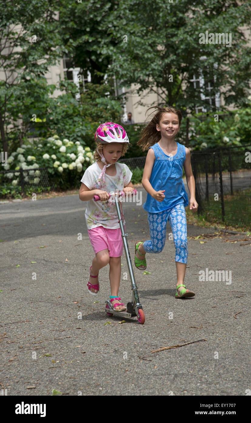 Bambini che giocano in un parco pubblico di New York STATI UNITI D'AMERICA avente una gara un bambino in esecuzione al fianco di un pilota di scooter Foto Stock