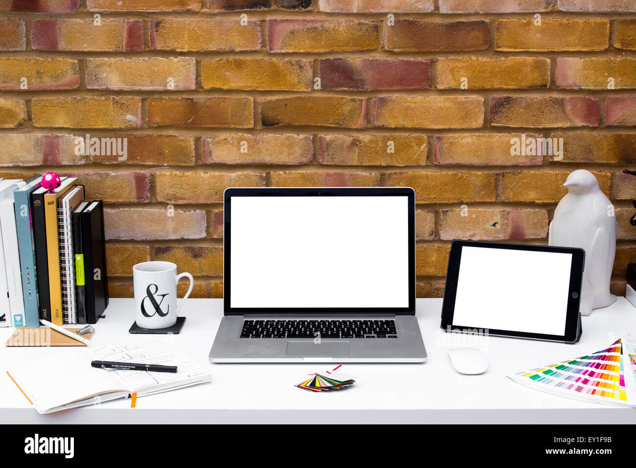 Creative Home Office space con progettisti grafici scrivania con computer portatile contro un muro di mattoni. Foto Stock