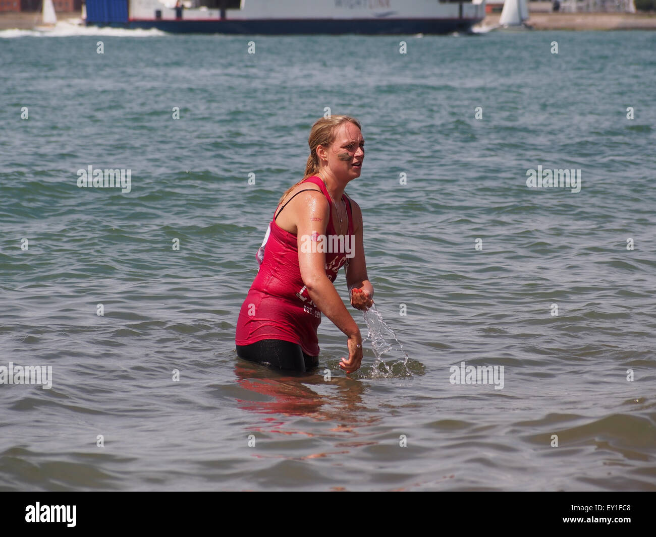 Una signora si raffredda e lavaggi fango dalla sua pelle in mare dopo la bella gara di fango per la vita a Southsea Foto Stock