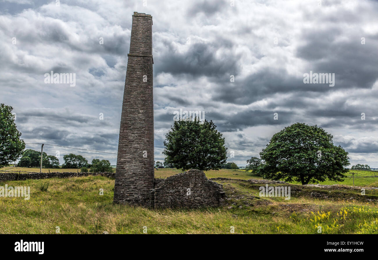 Torre in pietra e sbriciolamento muro di pietra a abbandonata miniera di piombo nel Peak District nel Derbyshire con un molto drammatico cielo nuvoloso. Foto Stock