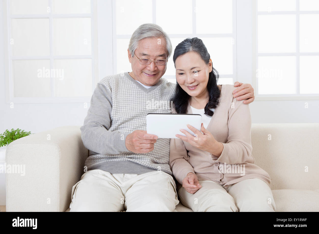 Coppia senior di detenzione e guardando il touch pad con il sorriso, Foto Stock