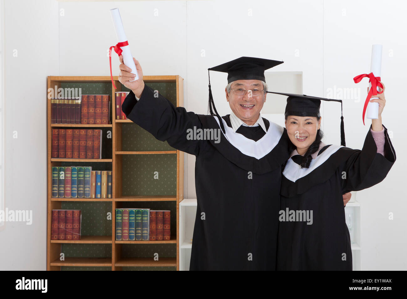 Coppia senior indossando abito di graduazione e diploma di contenimento con sorriso insieme, Foto Stock