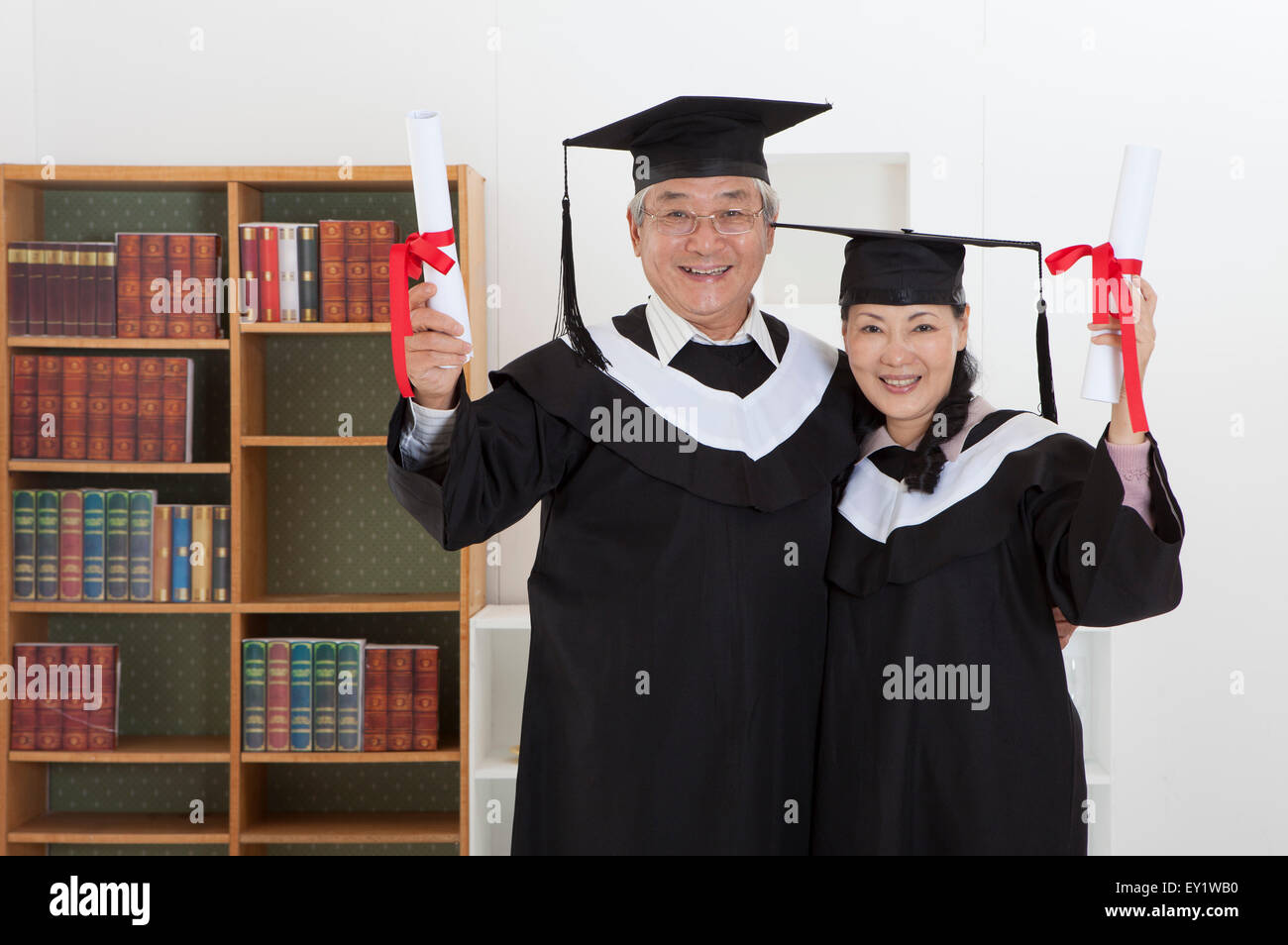 Coppia senior indossando abito di graduazione e diploma di contenimento con sorriso insieme, Foto Stock