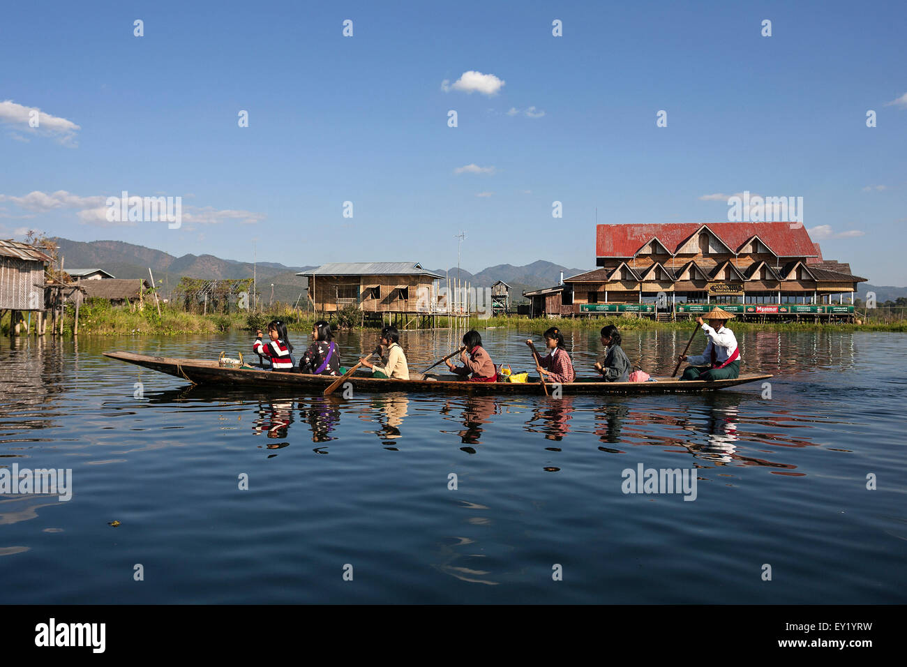Donne locali in una imbarcazione in legno kayak sul Lago Inle, palafitte dietro, Lago Inle, Stato Shan, Myanmar Foto Stock