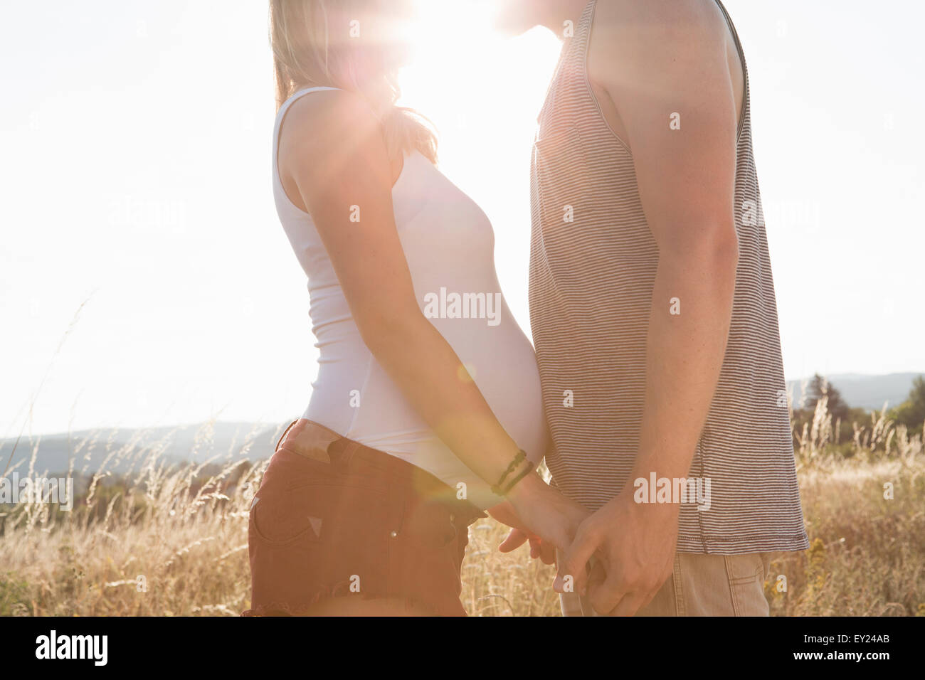 Giovane e incinta ragazza faccia a faccia e tenendo le mani nel campo Foto Stock