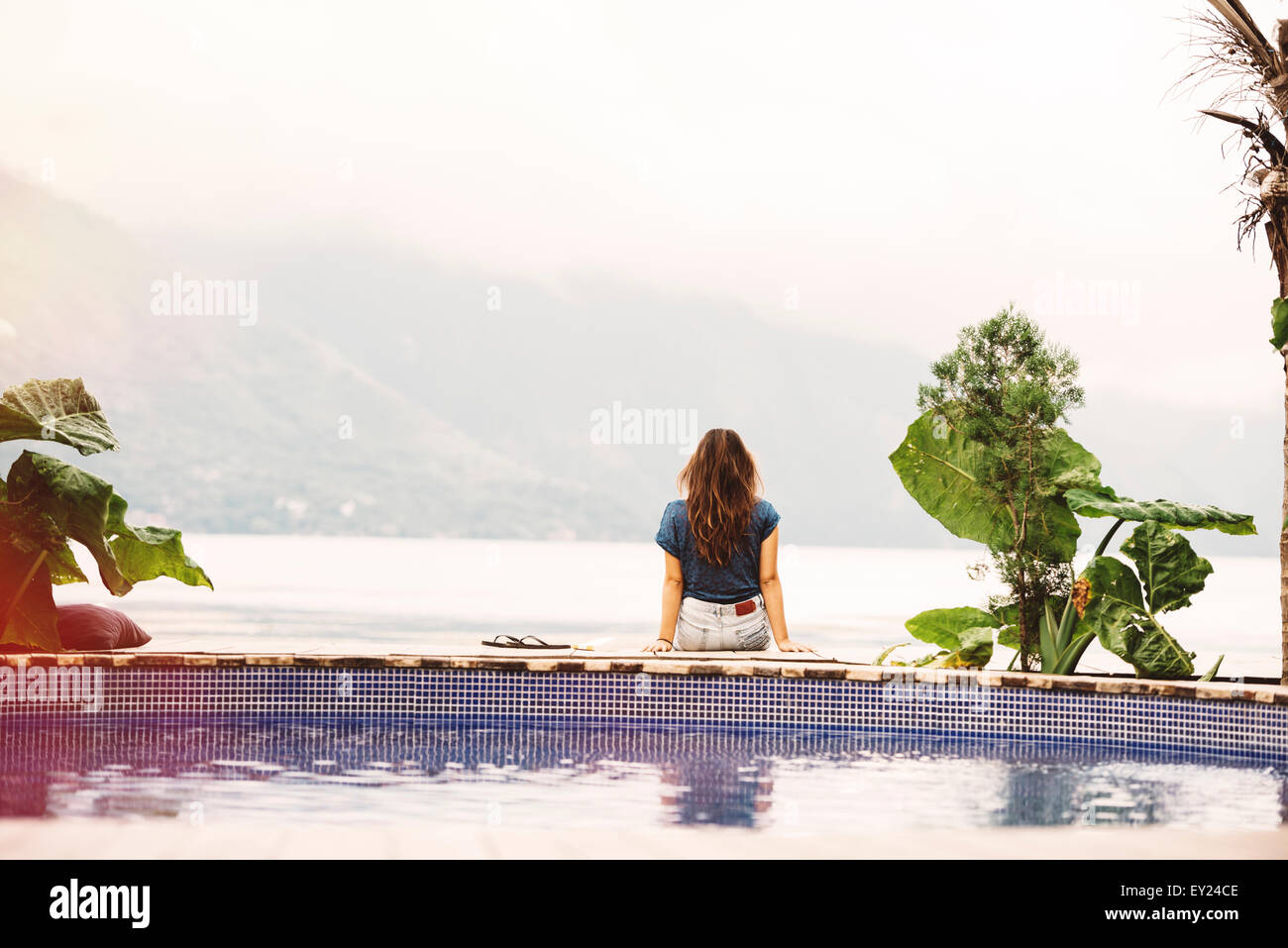 Giovane donna seduta sul bordo della piscina, San Pedro, lago Atitlan, Guatemala Foto Stock