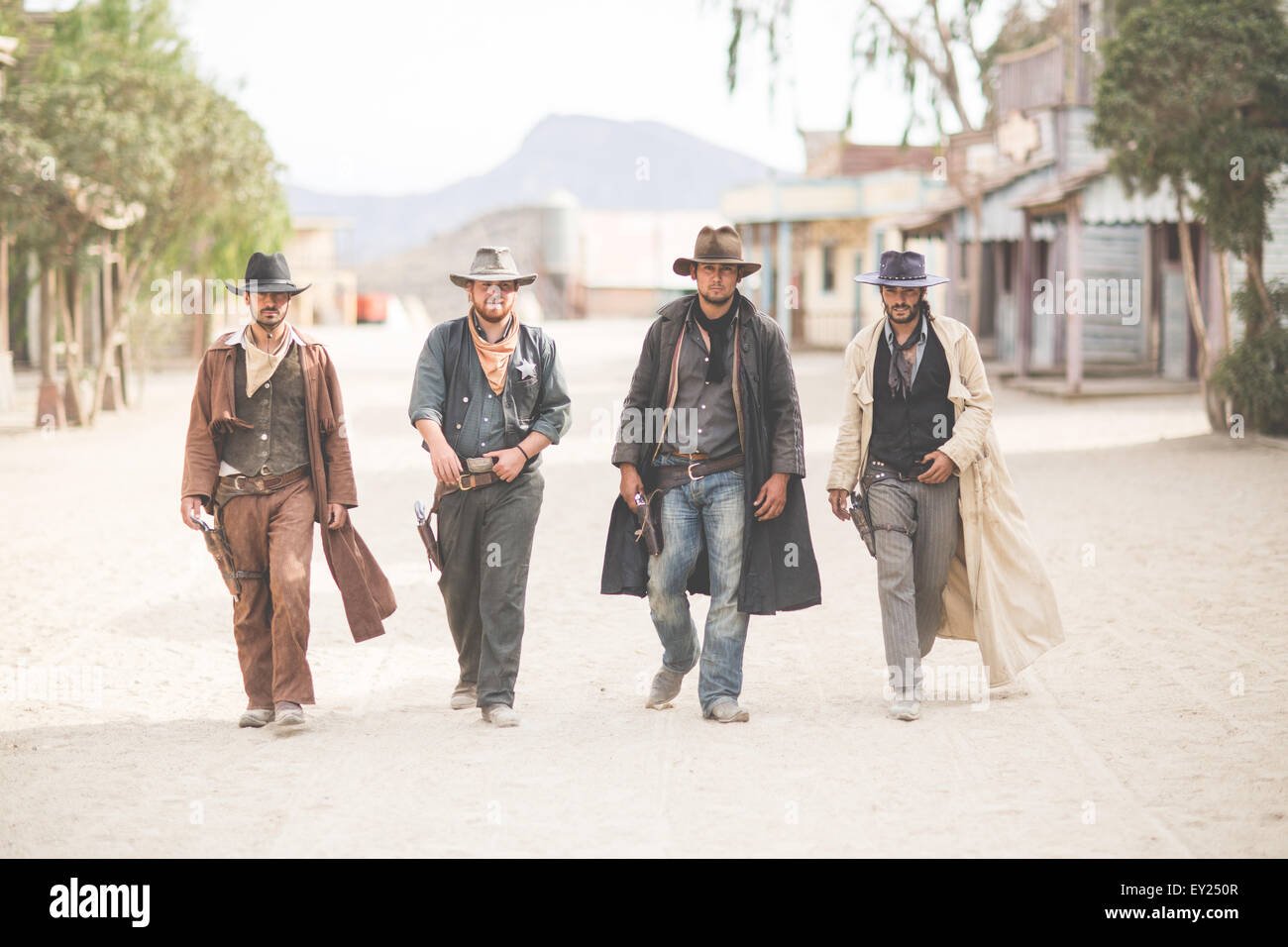 Ritratto di quattro cowboy camminando lungo la strada sul selvaggio west set cinematografico, Fort Bravo, Tabernas, Almeria, Spagna Foto Stock