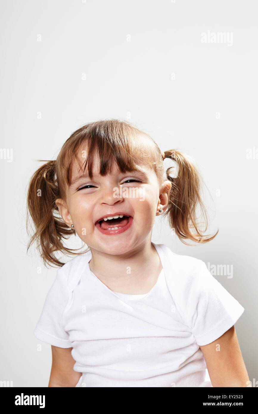Ritratto di giovane ragazza con pig-tail, ridendo Foto Stock