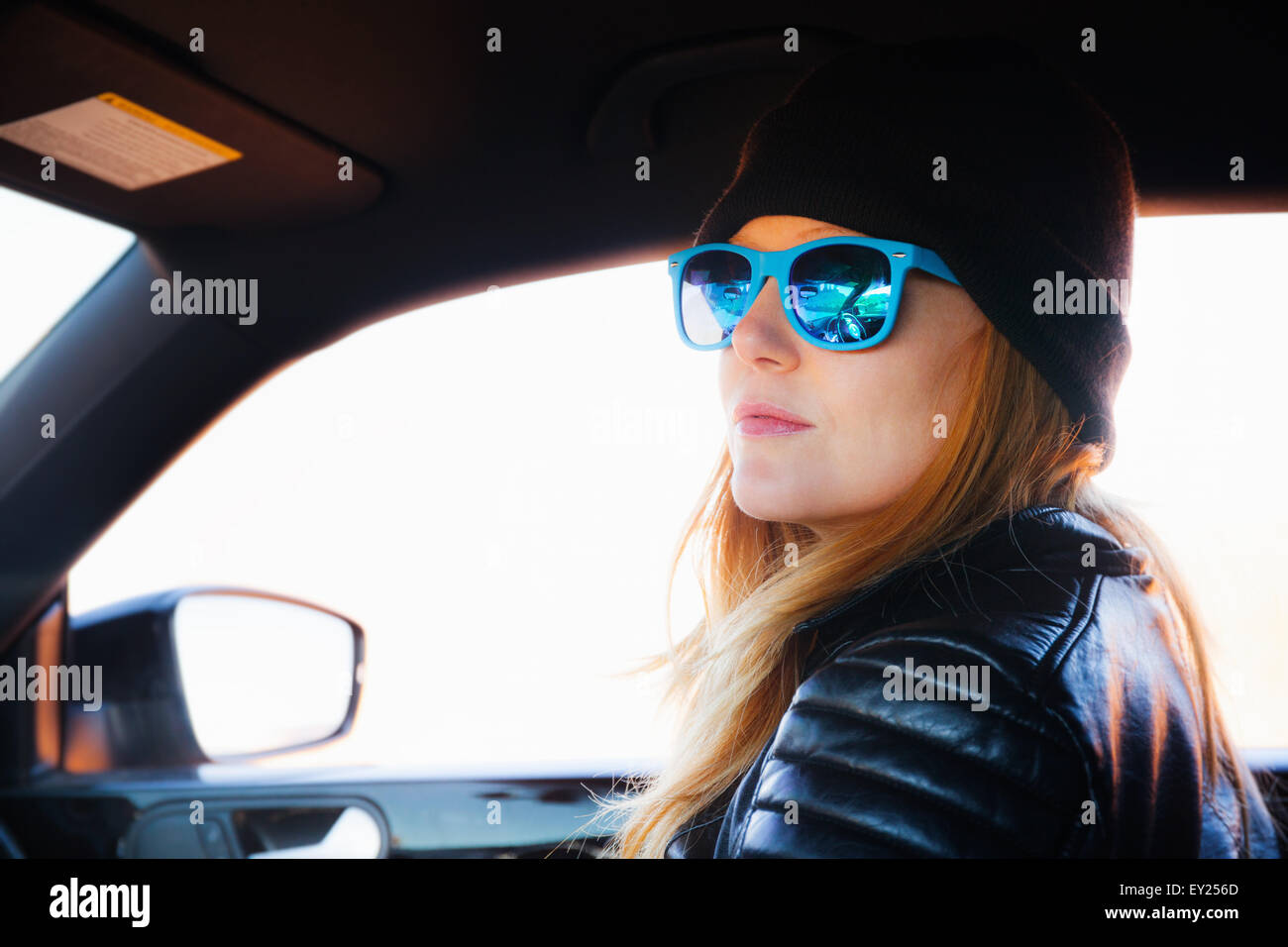 Ritratto di metà donna adulta su auto road trip indossando occhiali da sole blu Foto Stock