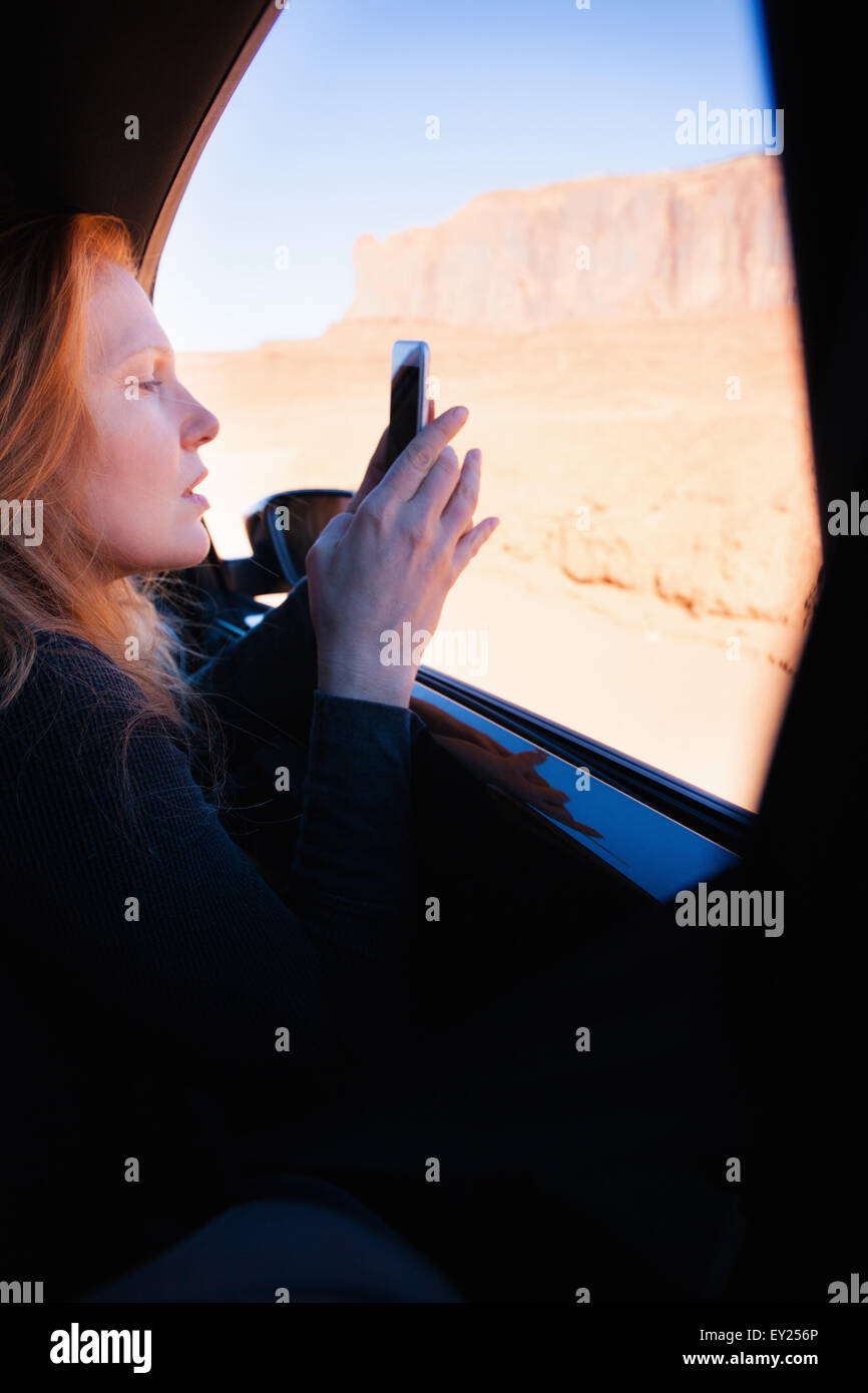 Donna fotografare sullo smartphone dal finestrino, Monument Valley, Utah, Stati Uniti d'America Foto Stock