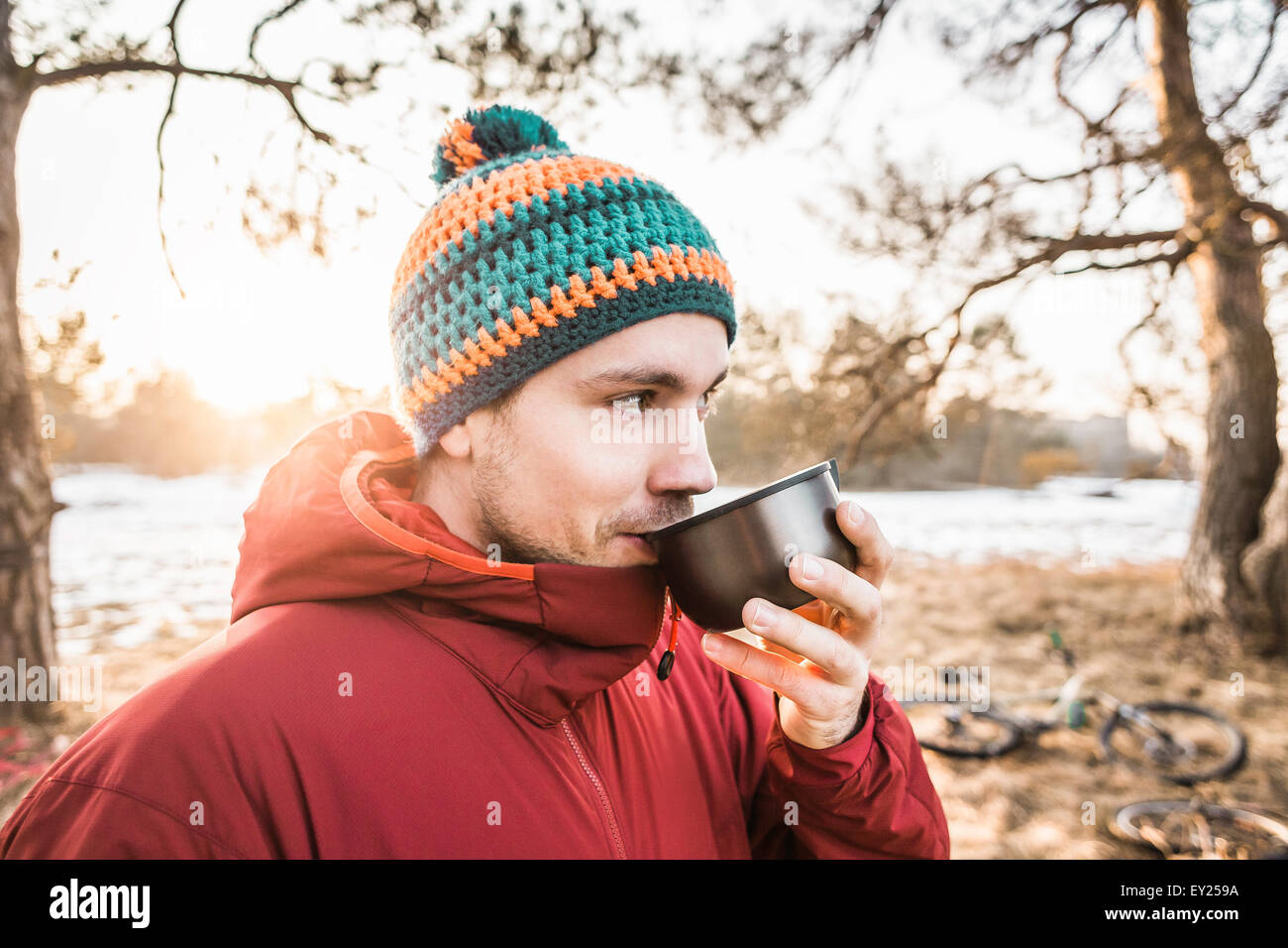 Ritratto di giovane maschio ciclista beve caffè nella foresta in riva al lago Foto Stock