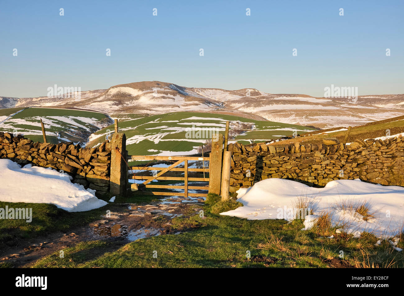 Gateway a un drammatico Peak District paesaggio con resti di tardo inverno neve bagnata in sera la luce del sole. Foto Stock